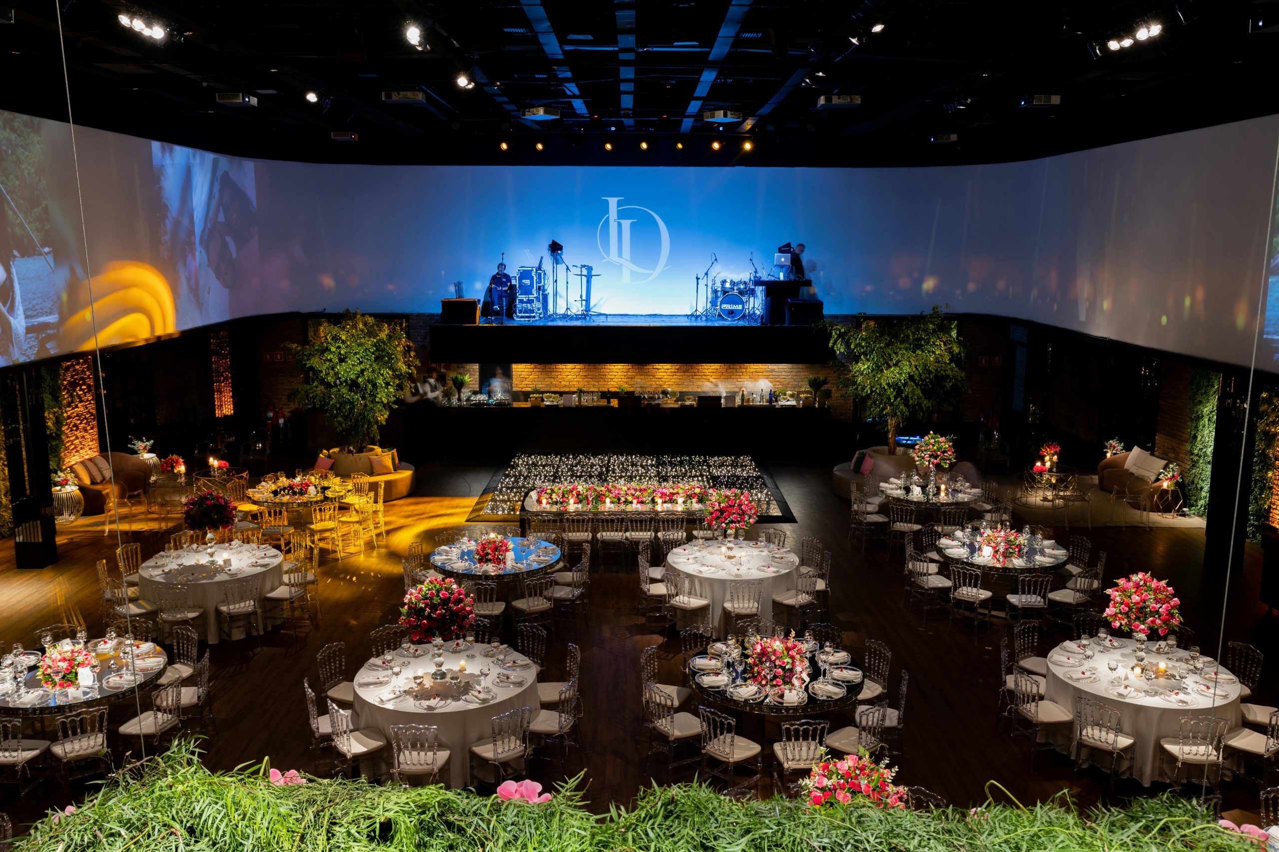 Luxurious banquet hall with floral centerpiece tables and stage setup for events.